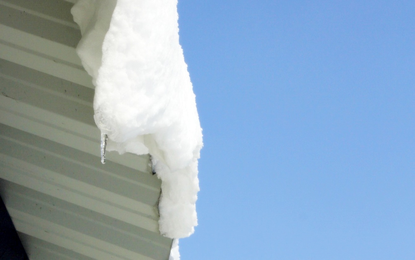 Na zdjęciu widać śnieg zalegający na dachu oraz sopel lodu